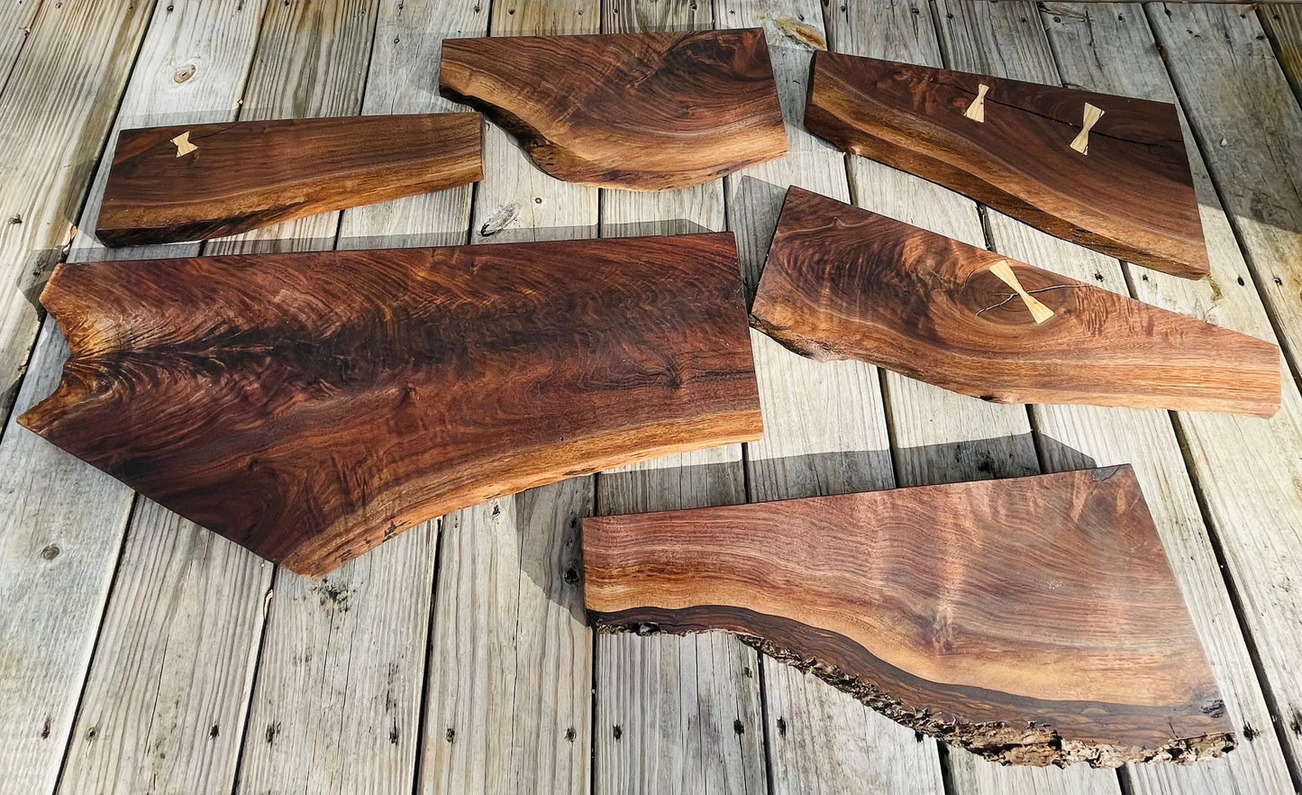 Black walnut live edge charcuterie boards, some featuring wood bow tie inlays. 